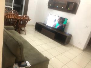 a living room with a couch and a flat screen tv at Odil in Praia Grande