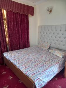 a bed in a bedroom with red curtains at Galaxy apartments , Galaxy hotel in Lower Topa