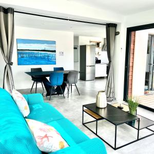 - un salon avec un canapé bleu et une table dans l'établissement La Villa Canopée - Piscine chauffée-Fibre-Clim-Jacuzzi, à Gujan-Mestras