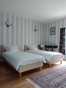 two beds in a bedroom with striped walls at Maison de campagne in Ambleny