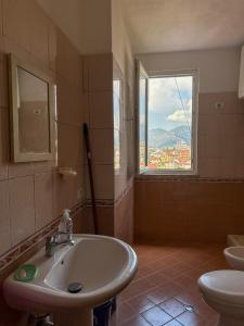 baño con lavabo y ventana con vistas. en YourHome Vilat Gjermane, en Tirana