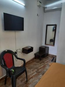 a room with a chair and a television on the wall at Cherry blossom guest house in Arpora