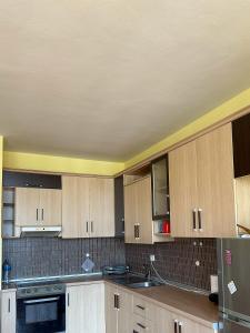 una cocina con armarios de madera y electrodomésticos de acero inoxidable en YourHome Vilat Gjermane, en Tirana
