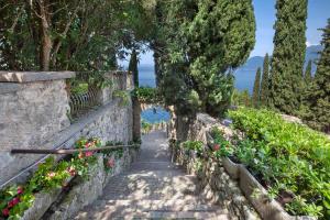 a path through a garden with flowers and trees at Leonardo Walsh Apartment With Lake View in Torri del Benaco