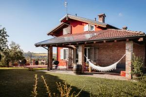 a red house with a hammock in front of it at Villa Gramolina Nizza in Nizza Monferrato
