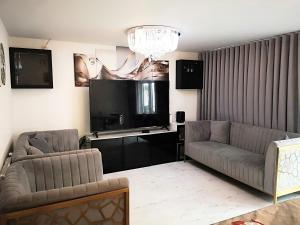 a living room with two couches and a flat screen tv at Harrow Home in Harrow