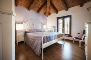a bedroom with a white bed and a wooden floor at Villa Gramolina Nizza in Nizza Monferrato