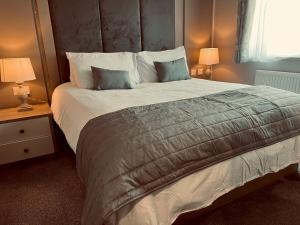 um quarto com uma cama grande, 2 mesas de cabeceira e 2 candeeiros. em Pass the Keys Luxury Lakeside Lodge em New Romney