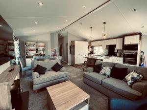 a living room with two couches and a kitchen at Pass the Keys Luxury Lakeside Lodge in New Romney