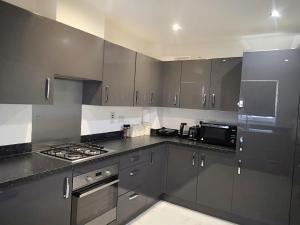 a kitchen with stainless steel appliances and black cabinets at Harrow Home in Harrow