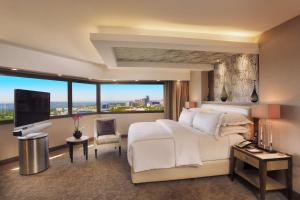 a bedroom with a large white bed and a large window at Sandton Sun and Towers in Johannesburg