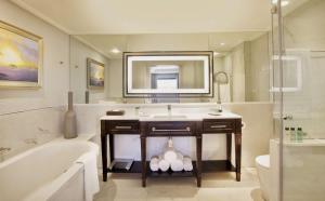 a bathroom with a tub and a sink and a bath tub at Sandton Sun and Towers in Johannesburg
