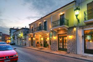 a street with a red car parked in front of buildings at Artemis Hotel in Delfoi
