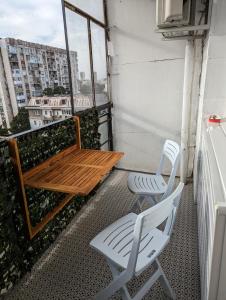 einen Balkon mit einer Holzbank und 2 Stühlen in der Unterkunft Teo's place in Ruse