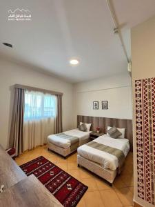 a hotel room with two beds and a window at اجنحة مجمع القوافل الفندقيه in Tabuk