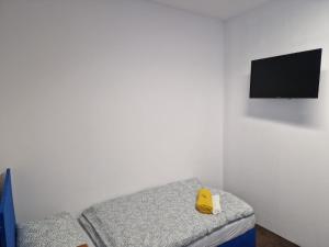 a room with a couch with a tv on a wall at NOCLEGI WOJTEK in Bytów