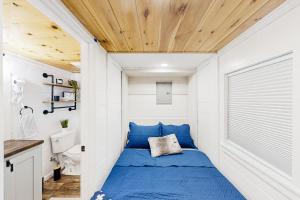 Mills RiverにあるCozy Lakeview Cottageの小さな家の中に青いベッドが備わる小さなベッドルームがあります。