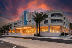 a large building with a palm tree in front of it at Hyatt Place St Augustine Vilano Beach in Saint Augustine