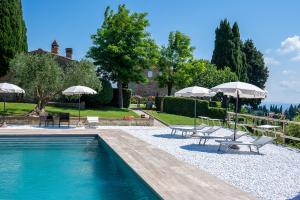 a swimming pool with umbrellas and lounge chairs next to a house at Villa delle Torri - Teloni in San Gimignano