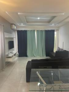 a living room with a black couch and a television at AlanVal Apartments in Accra