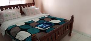 Una cama con marco de madera con una bolsa azul. en Kaks apartments, en Kampala