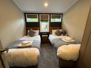 twee bedden in een kleine kamer met twee ramen bij Woolverstone Marina and Lodge Park in Ipswich