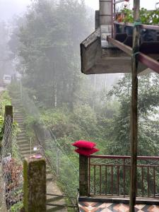 a red umbrella sitting on a balcony in the rain at Syengden Nikunj in Darjeeling
