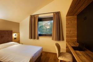a bedroom with a bed and a window with a chair at Valgrisa Mountain Lodges 1 in Valgrisenche