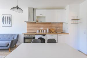 - une cuisine avec des placards blancs, une table et des chaises dans l'établissement IKIZEN - Central Confort - Hypercentre - place d'erlon, à Reims