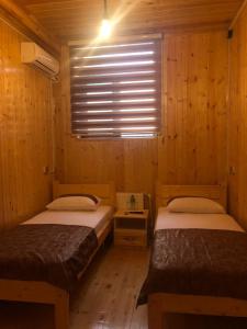 two beds in a wooden room with a window at WOOD MOTEL in Mingachevir