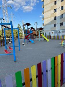 a playground with colorful play equipment and a fence at Jasmine Apartment in Iaşi