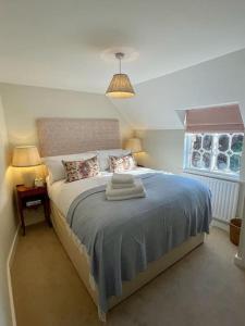 una camera da letto con un letto con una coperta blu e una finestra di Northbrook Cottage, Farnham, up to 8 adults a Farnham