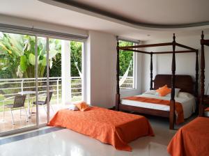 a bedroom with two beds and a balcony at Hotel Mirador Las Palmas in Armenia