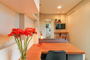 une chambre avec une table sur laquelle se trouve un vase de fleurs rouges dans l'établissement Ap Embarcadero, à Porto Alegre