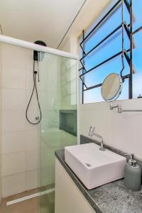 een badkamer met een wastafel, een douche en een spiegel bij Ap Embarcadero in Porto Alegre