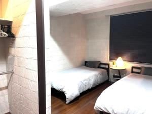 1 dormitorio con 2 camas y pared de ladrillo en Shibuya Harajuku big house, en Tokio