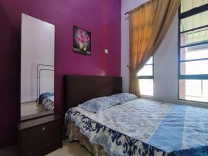 - une chambre avec un lit et un mur violet dans l'établissement NikNa Homestay Batu Rakit - WIFI, à Kampong Ru Tujoh