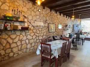 una sala da pranzo con tavolo e parete in pietra di La Casa D' Irene a Ayios Nikitas