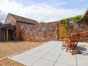 a patio with two chairs and a stone wall at Bumblebee Cottage in Wellington