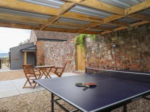 una mesa de ping pong en un patio con una pared de piedra en Bumblebee Cottage, en Wellington