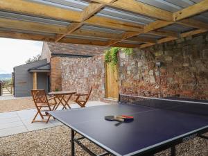 a ping pong table on a patio with a stone wall at Bumblebee Cottage in Wellington