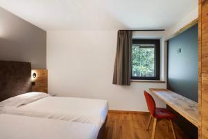 Schlafzimmer mit einem Bett, einem Schreibtisch und einem Fenster in der Unterkunft Valgrisa Mountain Lodges 2 in Valgrisenche