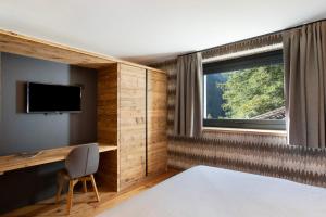 Schlafzimmer mit einem Bett, einem Schreibtisch und einem TV in der Unterkunft Valgrisa Mountain Lodges 2 in Valgrisenche