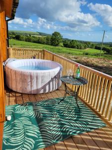 a large tub sitting on a deck with a table at Hot Tub Unique Farm Stay in Pallis Bridge