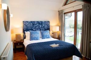 a bedroom with a blue and white bed with a window at Azalea Northbrook Park Chalet in Farnham