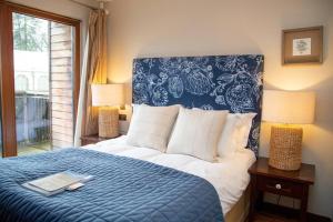 a bedroom with a blue and white bed with a laptop on it at Azalea Northbrook Park Chalet in Farnham