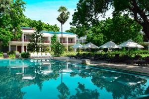 a swimming pool in front of a resort with trees and umbrellas at Anantamaa Hotel in Trincomalee