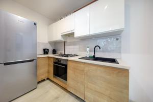 une cuisine avec des armoires blanches et un réfrigérateur en acier inoxydable dans l'établissement Crystal Apartment Katowice II, à Katowice