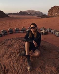 a woman sitting on a rock in the desert at Star World Camp in Wadi Rum
