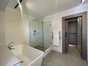 a white bathroom with a shower and a sink at Aquarella 2 in Plettenberg Bay